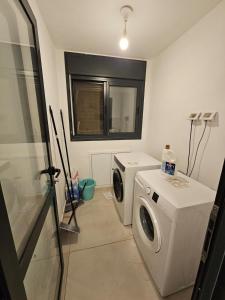 une buanderie avec une machine à laver et une fenêtre dans l'établissement Neveh Shamir Staycation, à Bet Shemesh