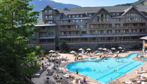 un grand hôtel avec une piscine et des gens assis autour dans l'établissement 1428 Lodge At Spruce Peak Ski In Ski In Ski Out King Studio By Stowe Mountain Rentals, à Stowe