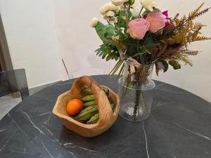 un panier de légumes sur une table avec un vase de fleurs dans l'établissement Private en - suite room near airport, à Madina