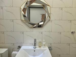 une salle de bain avec un lavabo et un miroir dans l'établissement Private en - suite room near airport, à Madina