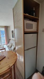 eine kleine Küche mit Kühlschrank und Mikrowelle in der Unterkunft Family Lodge Grand Tetras Les Angles in Les Angles