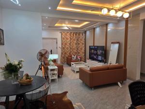 un salon avec un canapé, une télévision et une table dans l'établissement Private en - suite room near airport, à Madina