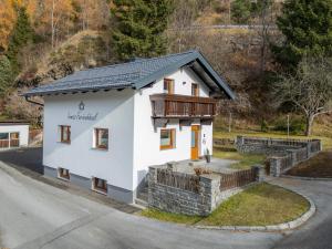 une petite maison blanche avec un balcon sur une rue dans l'établissement Irmas Ferienhäusl, à Längenfeld