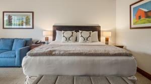 une chambre avec un grand lit et un canapé bleu dans l'établissement 1434 - Studio - Spruce Peak Lodge - Stowe Mt Resort - Ski in Ski out - Sleeps 4, à Stowe