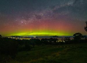 an aurora in the sky over a field at night at River Ridge Tiny House by Tiny Away in South Arm