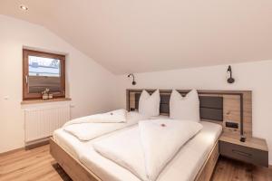 une chambre avec un grand lit blanc avec des oreillers blancs dans l'établissement Irmas Ferienhäusl, à Längenfeld