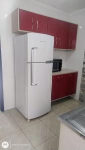 einen weißen Kühlschrank in einer Küche mit roten Schränken in der Unterkunft Casa Duplex com Vista pro Mar in Guaratuba