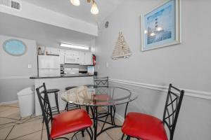 a dining room with a glass table and red chairs at Island Sunrise 362 by Youngs Suncoast in Gulf Shores