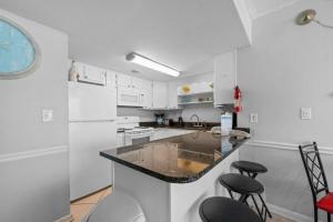 a kitchen with white cabinets and a counter with stools at Island Sunrise 362 by Youngs Suncoast in Gulf Shores +32 photos