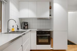 a kitchen with white cabinets and a sink and an oven at Northern Lights View Beautiful Berg in Kuberg