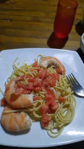 a plate of spaghetti with shrimp and tomatoes on it at Manglar escondido in Mompiche