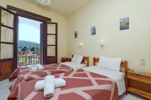 two beds in a room with a balcony at O Ampelonas tou kyr Giorgou in Skopelos Town