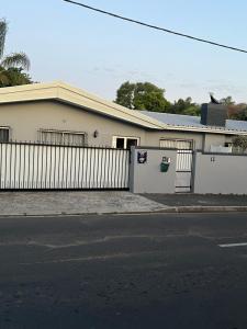 a white house with a fence and a street at Ridah's Accomodation in Bellville