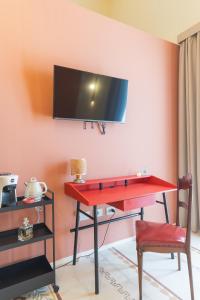 a red desk with a tv on a pink wall at L'Ombra dell'Ulivo B&b in Marsala