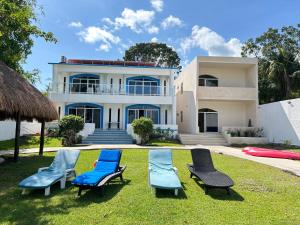 a house with blue lawn chairs in front of it at Departamentos Blue Bacalar in Bacalar
