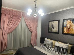 a bedroom with a bed with pink curtains and a chandelier at Cozy Comfort Flat , Madinaty in Cairo