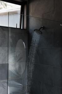a shower with a stream of water in a bathroom at The Huts in Ahipara