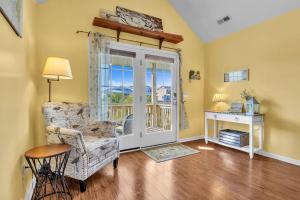 ein Wohnzimmer mit einem Stuhl und einem Fenster in der Unterkunft Seashell Cottage by Oak Island Accommodations in Oak Island