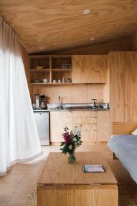 a living room with a table and a kitchen at The Huts in Ahipara