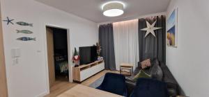 ein Wohnzimmer mit Sofa und Fernseher in der Unterkunft Apartament Zatoka Snów z widokiem na morze 3,5h od Wawy in Mechelinki + 37 Fotos