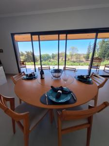 a dining room table with chairs and a large window at Casa Arara in Espirito Santo Do Pinhal