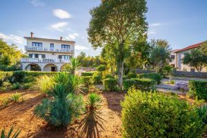 a garden in front of a large white building at Apartman Kačić in Sveti Ivan Dobrinjski