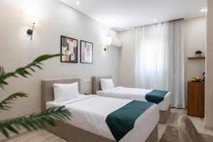 two beds in a hotel room with white and green sheets at Seven Stays New Cairo in Cairo