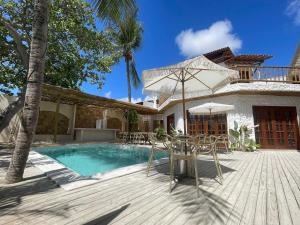 a pool with chairs and an umbrella next to a house at Villa da Praia -Orla de Atalaia in Aracaju
