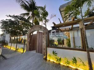 a house with a wooden gate and a palm tree at Villa da Praia -Orla de Atalaia in Aracaju +2 photos
