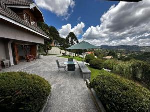 Un patio con una mesa y sillas y una sombrilla. en Chalé Luxuoso Capivari em Campos do Jordão, en Campos do Jordão
