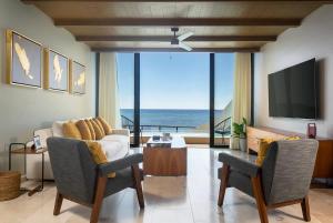 a living room with a couch and a tv at Beachfront 2BR Condo, Private Pool & Tankah Bay in Tulum