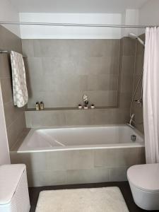 La salle de bains est pourvue d'une baignoire blanche et de toilettes. dans l'établissement Luxuriöse 3,5-Zimmer Wohnung für Familien und Geschäftsreisende mit Glasfaser-Internet, à Cham