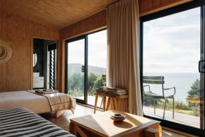 a bedroom with a view of the ocean at The Huts in Ahipara