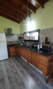 eine Küche mit Holzschränken und einer schwarzen Arbeitsplatte in der Unterkunft Cabaña Cina Cina in Villa Larca + 5 Fotos