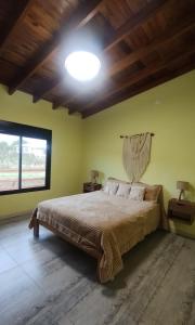 ein Schlafzimmer mit einem Bett und einem großen Fenster in der Unterkunft Cabaña Cina Cina in Villa Larca