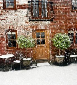 un bâtiment en briques avec des tables et des chaises et une porte en bois dans l'établissement Romantic Country Cottage with log burner, garden patio, outdoor tub and country views- Brecon Beacons National Park, à Llangadog