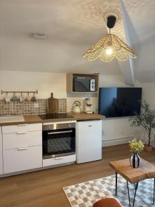 Il comprend une cuisine équipée d'une cuisinière. - un four supérieur à côté d'une télévision dans l'établissement Charmant appartement - Le Dopamine, à La Roche-sur-Yon