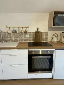 une cuisine avec des armoires blanches et un four à plaques de cuisson dans l'établissement Charmant appartement - Le Dopamine, à La Roche-sur-Yon