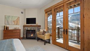 a bedroom with a fireplace and a chair and a television at STOWE GLOBE 4 BEDROOM LUXURY CABIN SKI IN SKI OUT By Stowe Mountain Rentals in Stowe