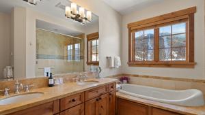 a bathroom with two sinks and a tub and a large mirror at STOWE GLOBE 4 BEDROOM LUXURY CABIN SKI IN SKI OUT By Stowe Mountain Rentals in Stowe +31 photos