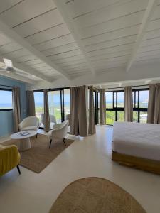 a bedroom with a bed and chairs and windows at Kainos Tropical Boutique Hotel in Las Terrenas
