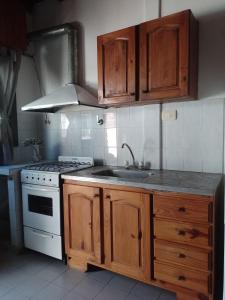 eine Küche mit Holzschränken, Spüle und Herd in der Unterkunft Mononorte in Mar de Ajó