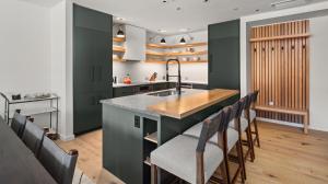 une cuisine avec des placards verts et un comptoir avec des chaises dans l'établissement Lux Mountainside 2 Bed Mountainside Condo By Stowe Mountain Rentals, à Stowe