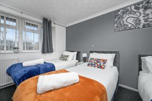 zwei Betten in einem Zimmer mit zwei Fenstern in der Unterkunft The Randolph 2-Bed MK9 Flat Short- Long-Stay Family & Contractor Friendly Free Parking close to Theatre, Now with lounge in Milton Keynes
