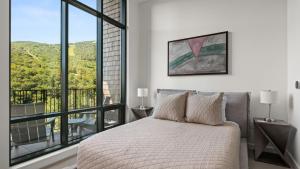 une chambre avec un lit et une grande fenêtre dans l'établissement New Spruce Peak Tree House Unit Steps To The Lifts With Big Mountain Views Sleeps 9 By Stowe Mountain Rentals, à Stowe