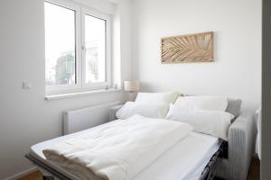 a white bedroom with two beds and a window at Modernes 1-Zimmer-Studio I Augsburg City in Augsburg