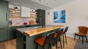 une cuisine avec des placards verts et un comptoir avec des tabourets dans l'établissement 409 3 bed Treehouse unit Spruce Peak at the Base of Stowe Mt Resort sleeps 9, à Stowe