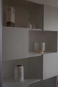 a white shelf with bowls and a box on it at Modernes 1-Zimmer-Studio I Augsburg City in Augsburg +4 photos