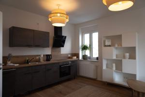 a kitchen with black cabinets and a sink at Modernes 1-Zimmer-Studio I Augsburg City in Augsburg