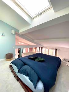 a bedroom with a large blue bed with a skylight at The Artist in Clichy